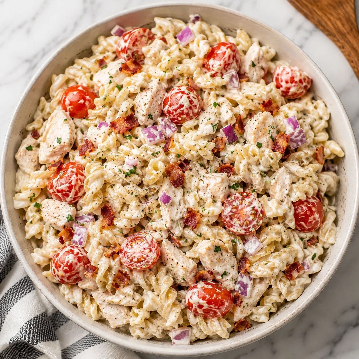 Chicken Ranch Pasta Salad with creamy ranch, tomatoes, bacon, chicken, and red onion in a white bowl