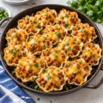 Taco ranch bites in a complete dark round skillet on a bright marble surface, with crisp ruffled shells, seasoned meat filling, melted cheese, and fresh herb garnish visible across the full dish.
